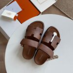 Sandali marroni di lusso su tavolo bianco, stile elegante e casual, perfetti per ogni occasione.