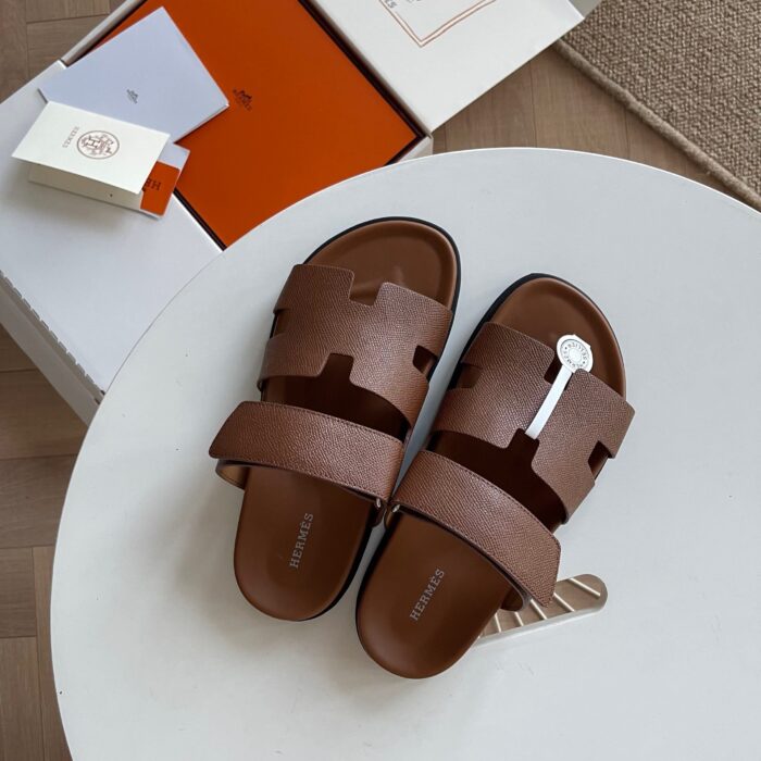 Sandali marroni di lusso su tavolo bianco, stile elegante e casual, perfetti per ogni occasione.