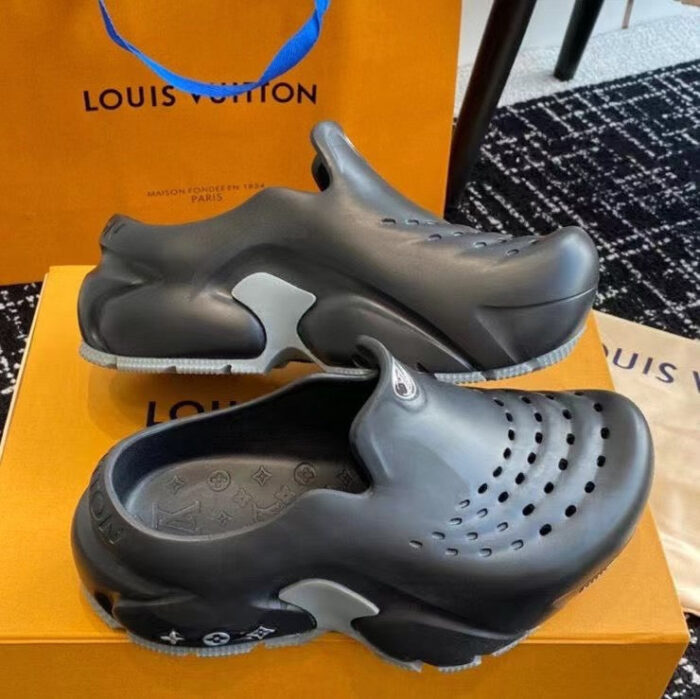 Scarpe moderne Louis Vuitton nere con dettagli grigi, su scatola arancione e tappeto nero elegante.