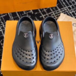 Scarpe slip-on nere di design moderno con logo di lusso su scatola arancione elegante.