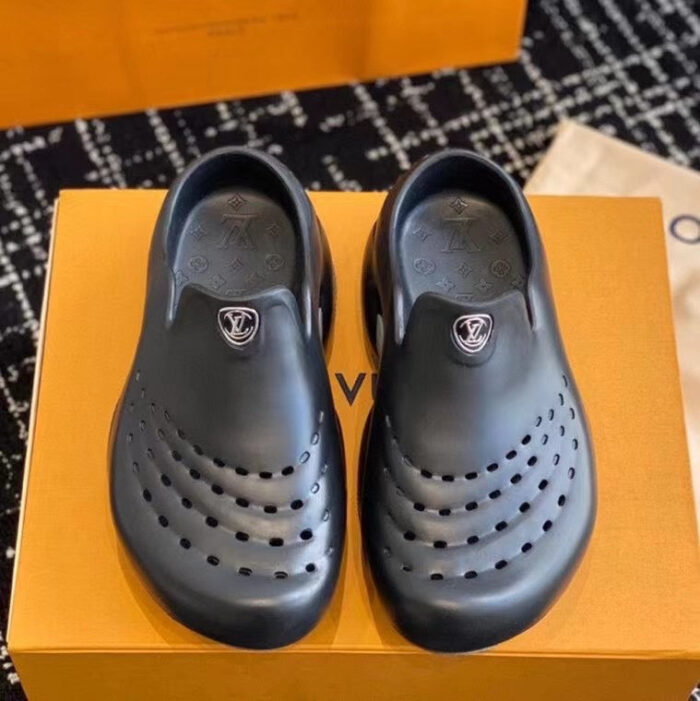 Scarpe slip-on nere di design moderno con logo di lusso su scatola arancione elegante.