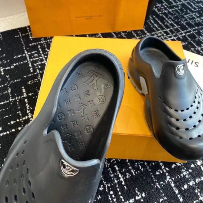 Scarpe slip-on nere di lusso con scatola elegante su tappeto moderno.