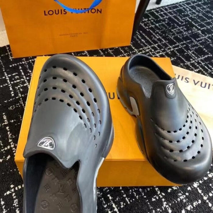 Sneakers di lusso nere con ventilazione, presentate su un elegante box arancione.