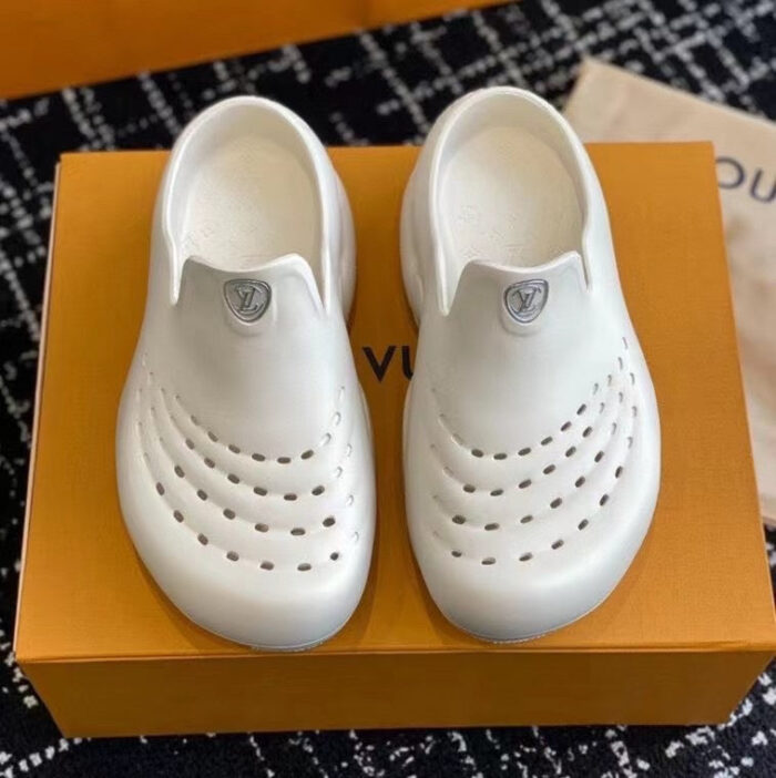 Scarpe moderne bianche con perforazioni su box arancione, stile minimalista e design elegante.