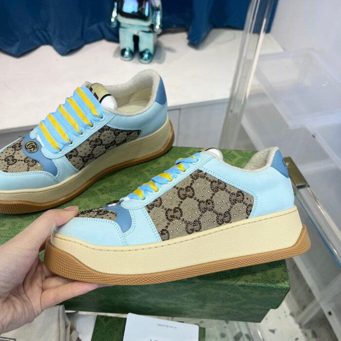 Sneakers di lusso blu con dettagli gialli e monogramma, stile elegante e moderno.