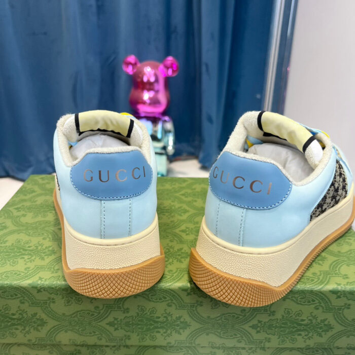 Sneakers Gucci blu beige con dettagli eleganti e tocco giocoso, presentate su una scatola decorativa.