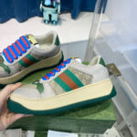 Sneakers alla moda con fasce colorate verde, arancione e suola spessa chunky, manico in mano.