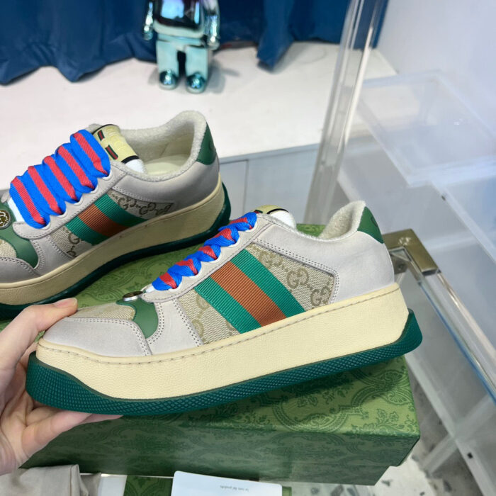 Sneakers alla moda con fasce colorate verde, arancione e suola spessa chunky, manico in mano.