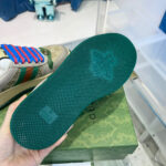 Sneaker di lusso con suola verde, dettagli eleganti e stile raffinato su box decorativo.