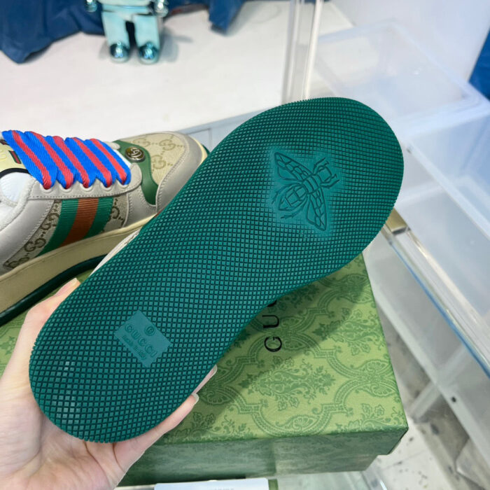 Sneaker di lusso con suola verde, dettagli eleganti e stile raffinato su box decorativo.