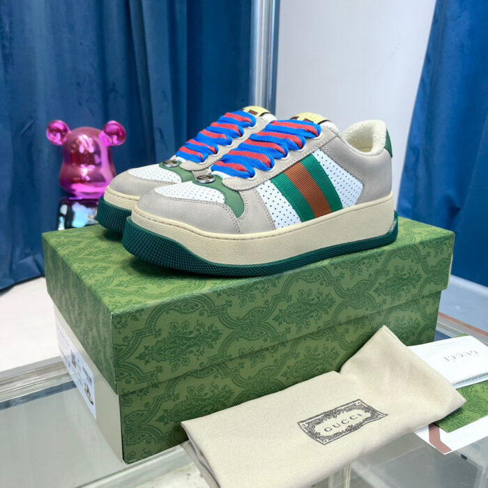 Sneakers di lusso con lacci blu, dettagli colorati e packaging elegante su sfondo blu e rosa.