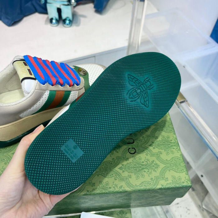Sneaker di lusso con suola verde, dettaglio baco e design colorato in contesto raffinato.