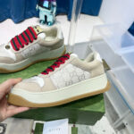 Sneaker Gucci beige con lacci rossi e suola platforme in gomma con trama esagonale.