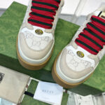 Sneakers Gucci eleganti con dettagli iconici, lacci rossi e design di lusso.