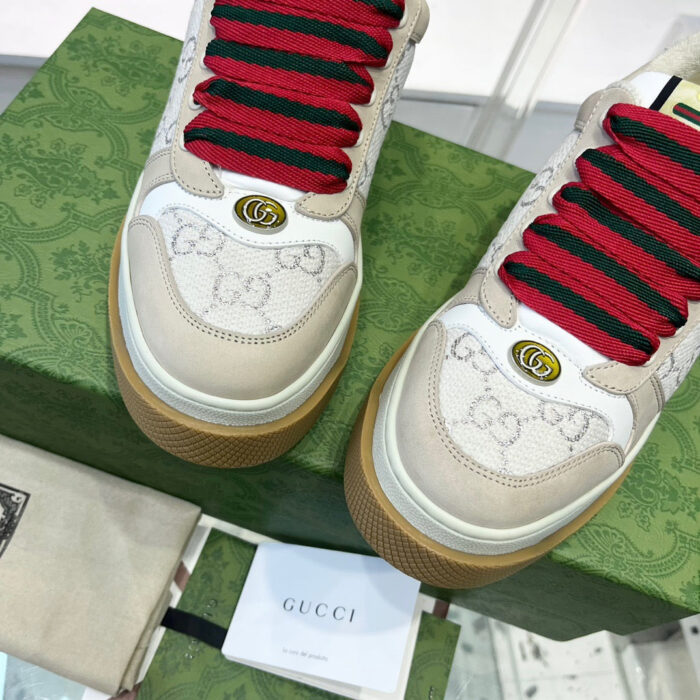 Sneakers Gucci eleganti con dettagli iconici, lacci rossi e design di lusso.
