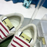 Sneakers trendy beige con strisce rosse e dettagli di alta qualità, ideali per stile e comfort.