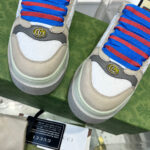 Sneakers moderne bianche con lacci blu e logo metallico, stile urbano e fashion.