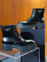 Stivali eleganti in pelle nera con logo triangolare, stile moderno e versatile per ogni look.