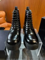Stivaletti neri lucidi, stile moderno, su stand trasparente in ambiente elegante.