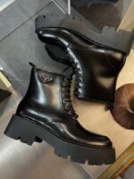 Stivaletti neri in pelle lucida con suola chunky e logo di design, stile moderno ed elegante.