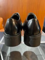 Scarpe Prada in pelle nera con tacco chunky elegante e dettagli di alta qualità.