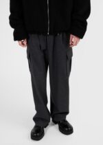Stile casual urbano con giacca nera, pantaloni cargo grigi e scarpe nere lucide.