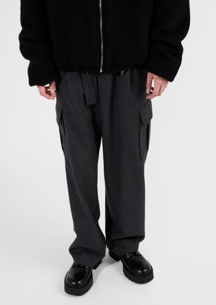 Stile casual urbano con giacca nera, pantaloni cargo grigi e scarpe nere lucide.