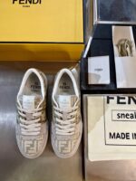 Sneakers Fendi di lusso con scatola gialla e dettagli eleganti su superficie metallica.