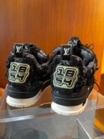 Sneakers di lusso nere con logo iconico e dettagli distressed in stile streetwear.