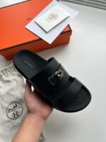 Sandalo nero di lusso con logo, confezione elegante e portaoggetti in tessuto.