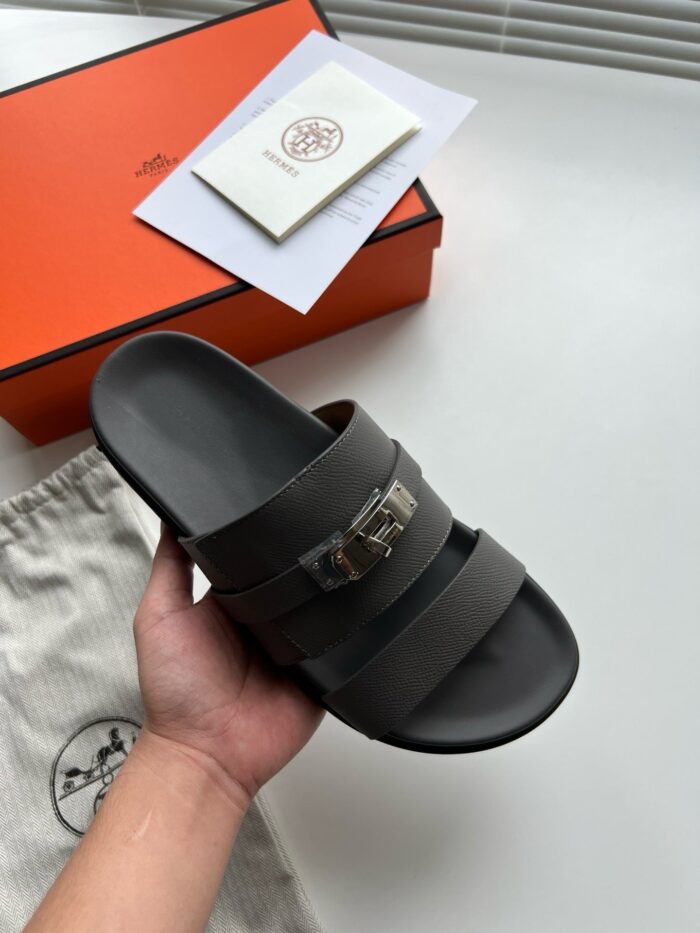 Sandali neri di lusso con logo metallizzato e packaging elegante, stile raffinato e trendy.