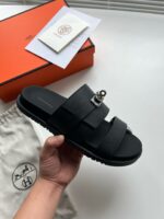 Sandalo nero di lusso con strap metallici, packaging elegante e dettagli raffinati.