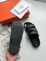 Sandali di lusso neri con cinturini perforati, logo e dettagli eleganti, perfetti per un look sofisticato.