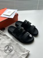 Sandali neri di design con scatola elegante e accessori di lusso, stile minimalista e raffinato.