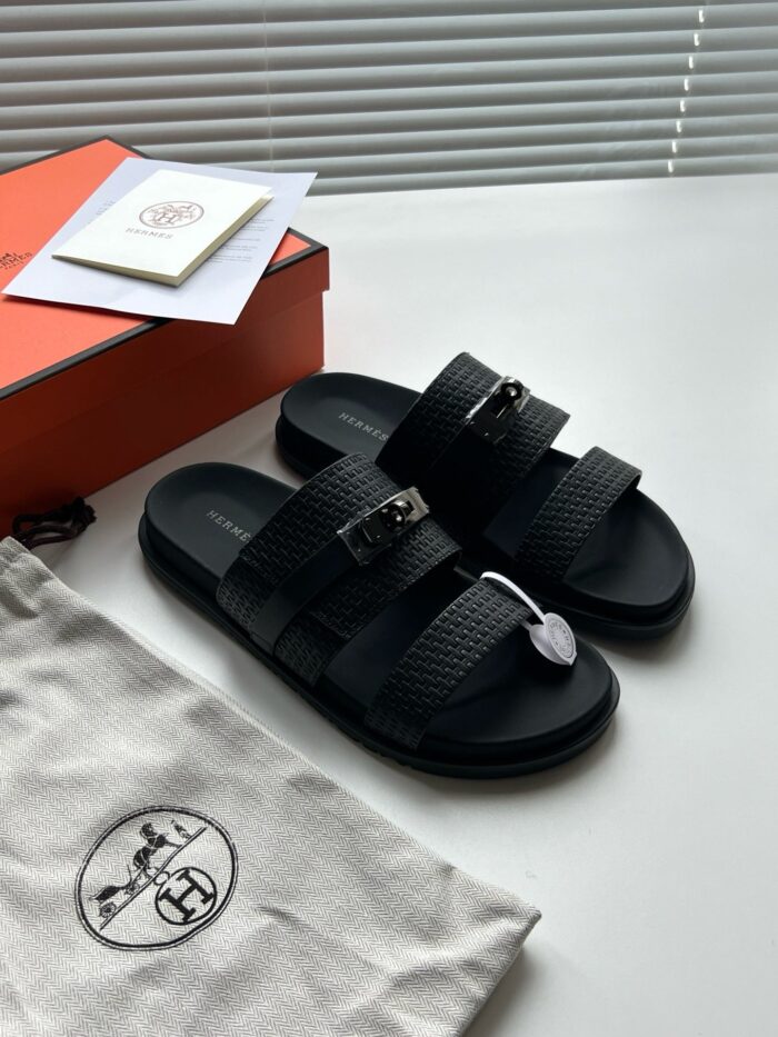 Sandali neri di design con scatola elegante e accessori di lusso, stile minimalista e raffinato.