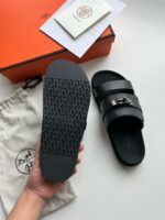 Sandali in pelle neri eleganti, con scatola arancione e custodia di lusso raffinata.