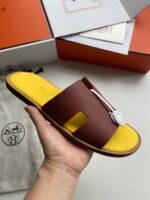 Sandalo Hermès in pelle con logo H, suola gialla e packaging di lusso.