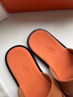 Sandali estivi minimalisti nero e arancio con punta ergonomica e logo embossato.