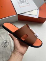 Sandali eleganti in pelle marrone con dettagli moderni e suola arancione, perfetti per ogni occasione.