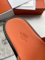 Interno di sandalo Hermès Paris con sole arancione, logo centrale e dettagli eleganti.