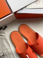 Scarpe slip-on arancioni minimaliste con packaging elegante e accessori coordinati, stile moderno e versatile.