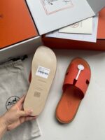 Sandali di lusso arancioni con packaging elegante e dettagli raffinati, ideali per uno stile sofisticato.