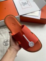 Sandalo slide arancione di design elegante con dettaglio bianco e suola leggera ideale per l’estate.