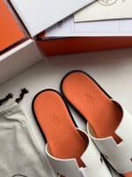 Sandali slide bianchi di lusso con suola arancione, design elegante e stile minimalista.