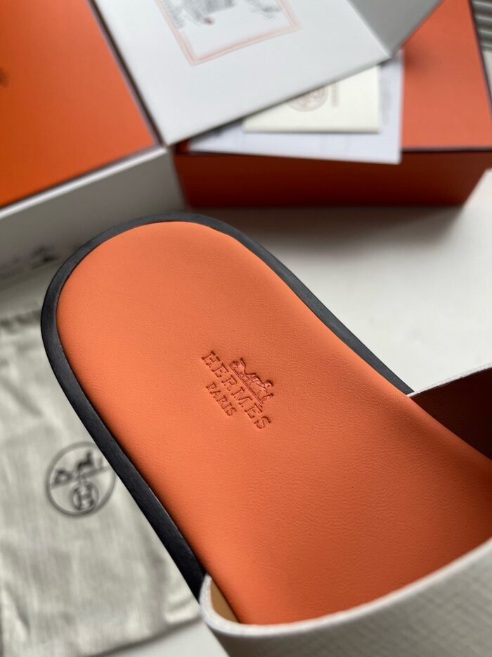 Sandalo slide di lusso con sole arancione, packaging elegante e dettagli raffinati.