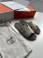 Sandali eleganti in tonalità neutre con packaging di lusso e dettagli artigianali.