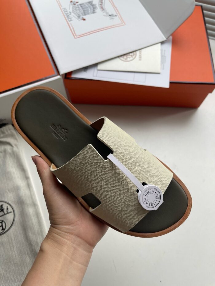 Sandalo beige di lusso con packaging elegante e tag distintivo, stile raffinato e moderno.