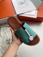 Sandalo slip-on verde menta con suola in pelle, packaging elegante, stile casual e raffinato.