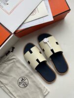 Sandali beige con suola navy, decorazione elegante e confezione di lusso.