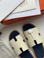 Sandali moderni di lusso con design elegante, dettaglio H e packaging premium sofisticato.